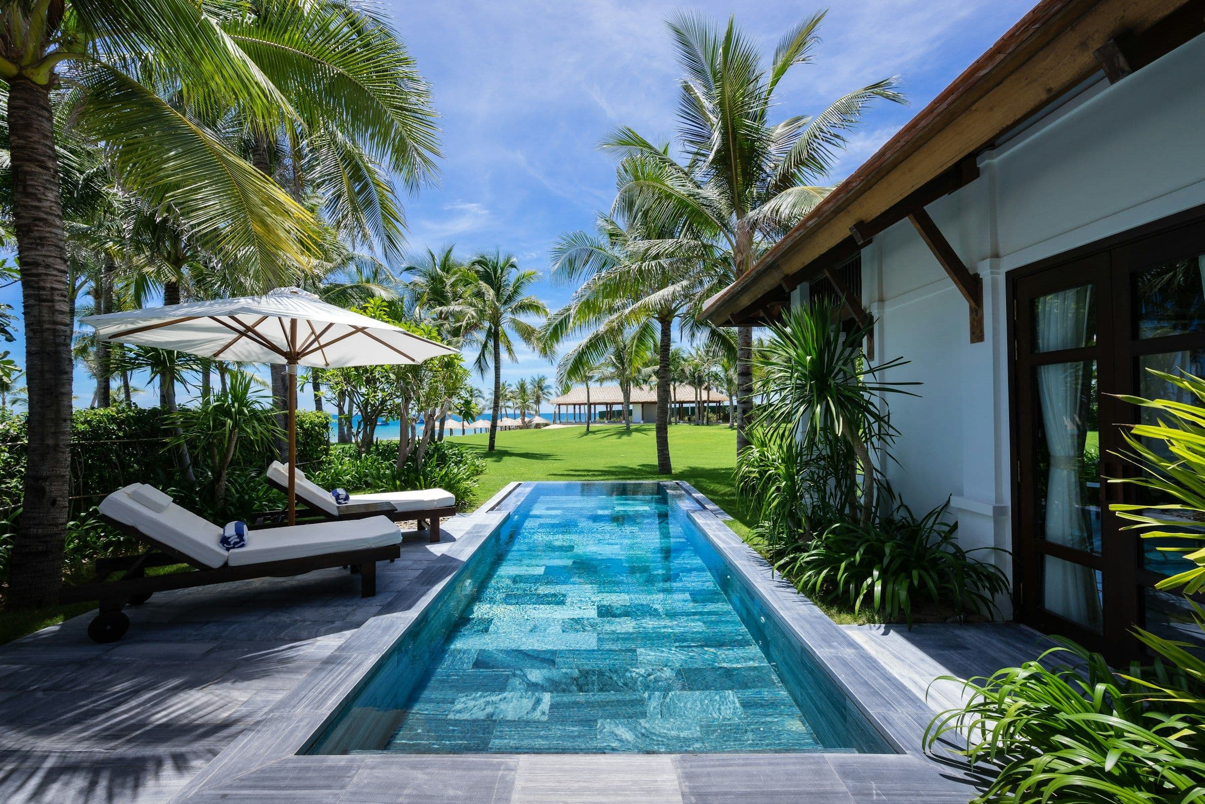 A private lap pool with sun loungers in the garden of a beachfront villa in Vietnam.