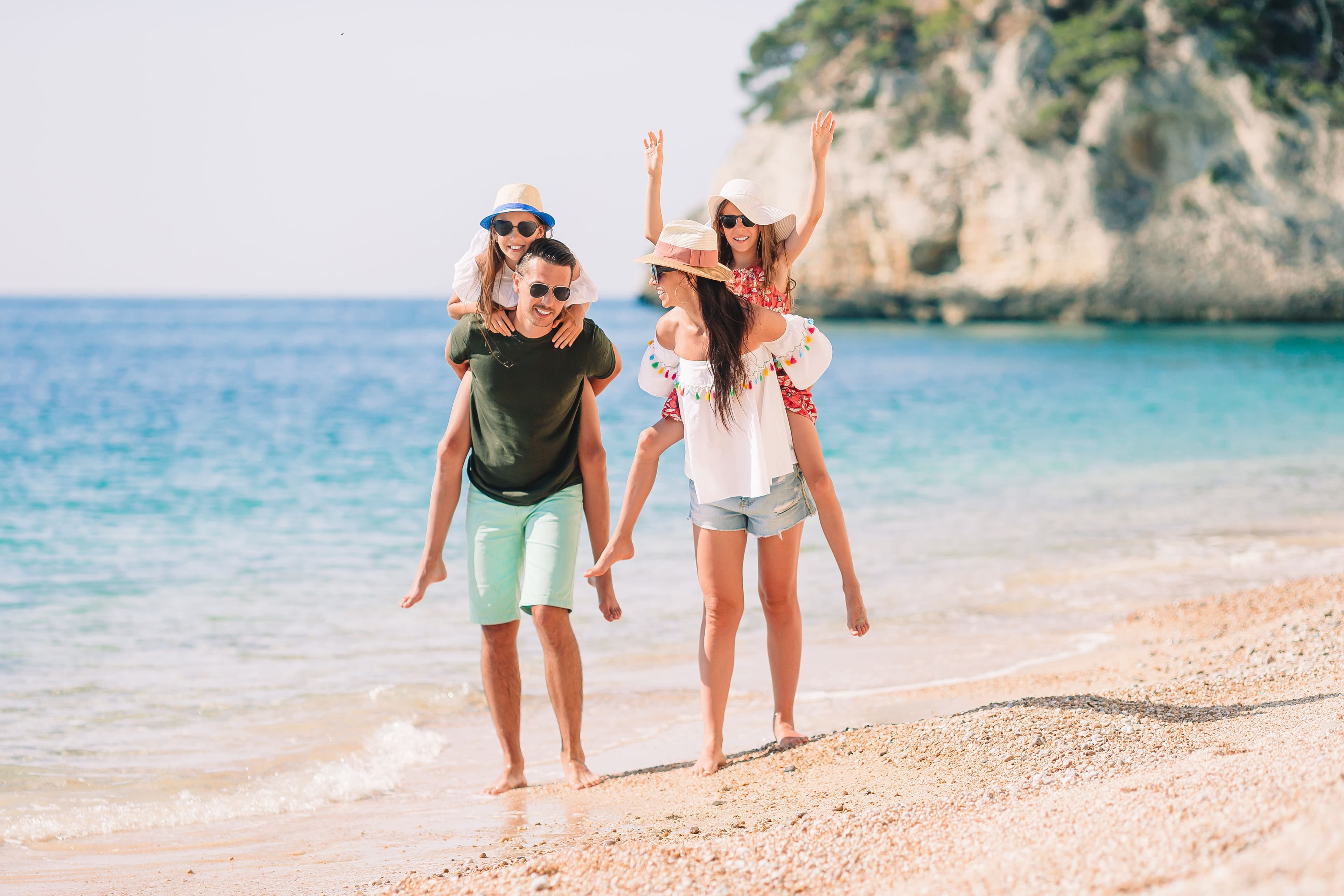happy family piggyback rides on sandy tropical beach