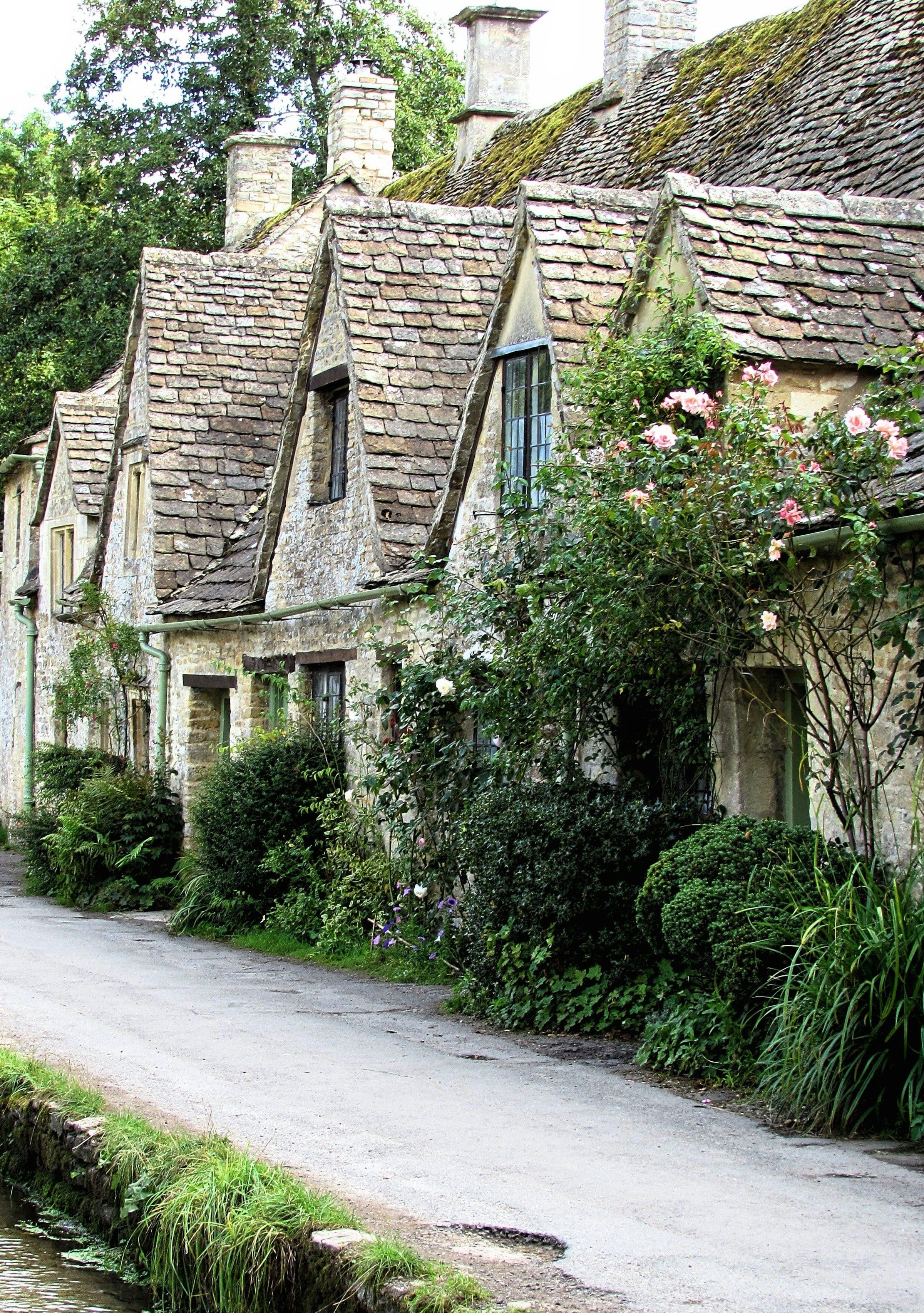 Stone cottages with flower-filled gardens in the village of Bibury in the Cotswolds.
