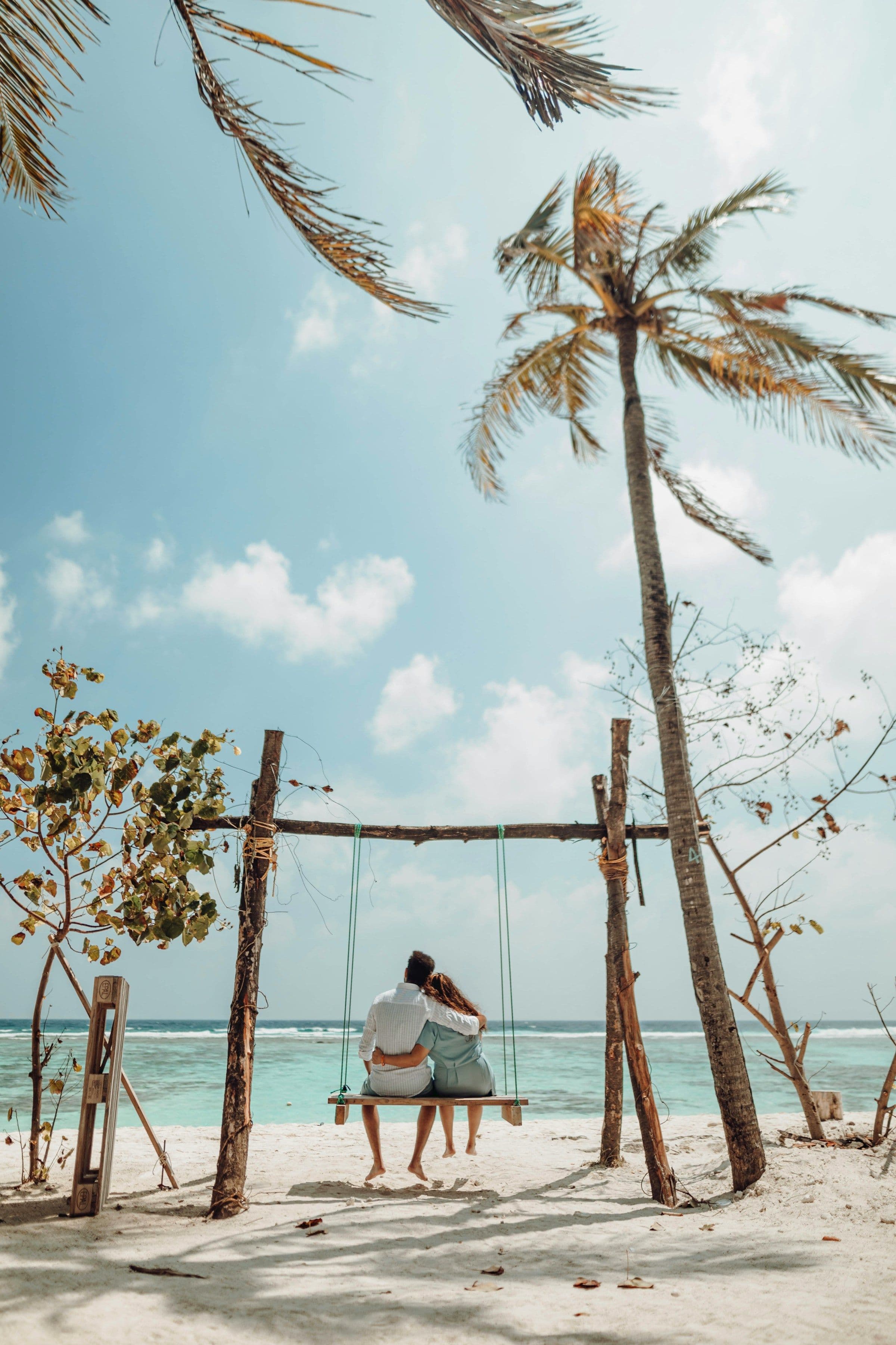 A swing hanging from a leaning palm tree on a white-sand beach in the Maldives.