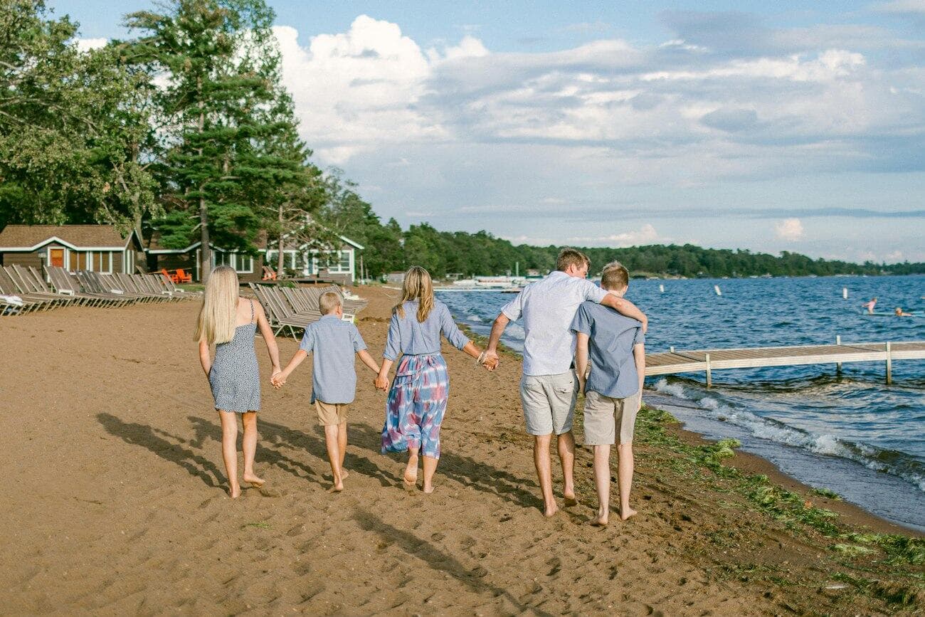 A family walking hand in hand along a sandy beach.