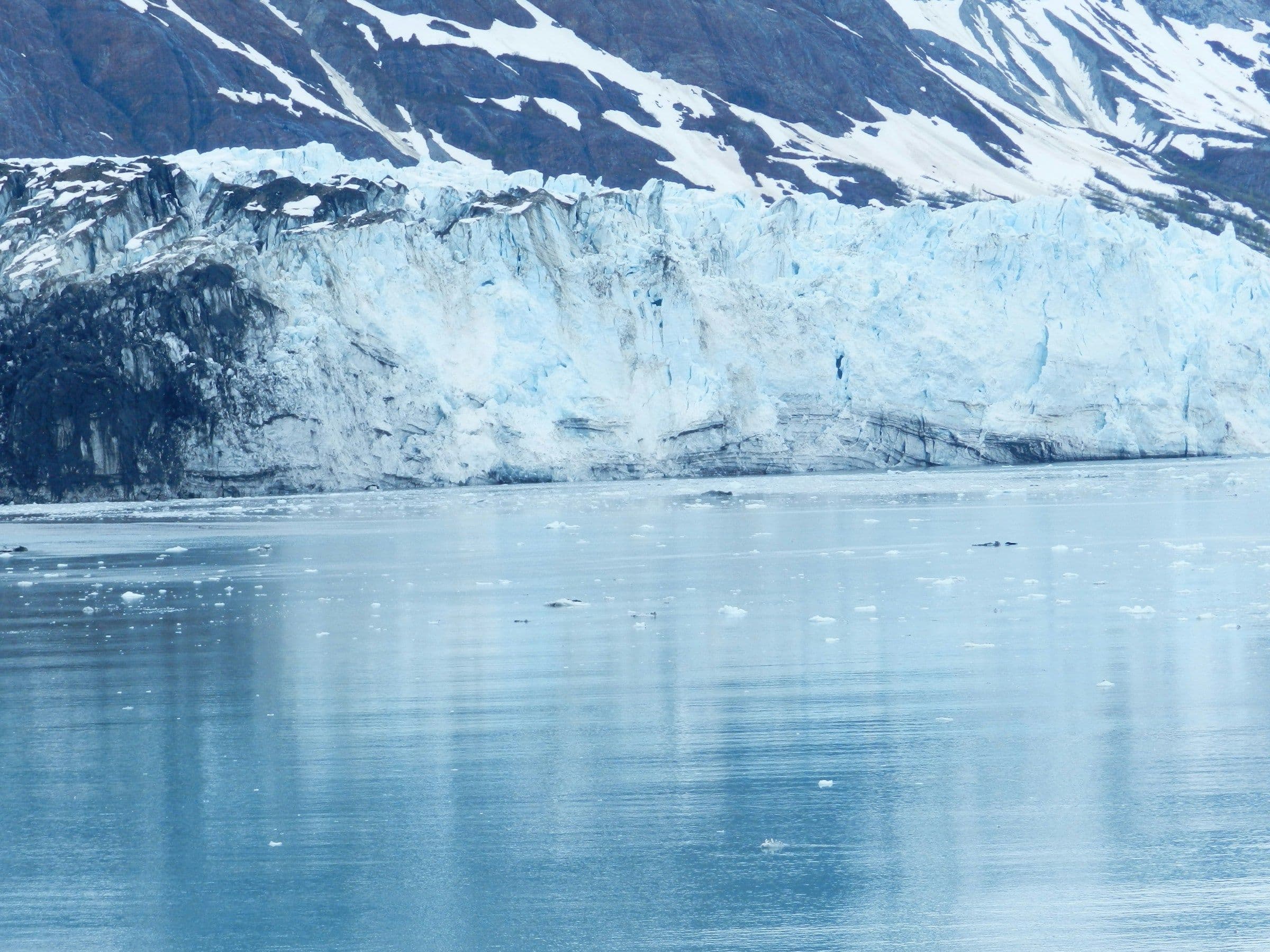 The face of a tidewater glacier reflected in still water in Glacier Bay, Alaska.