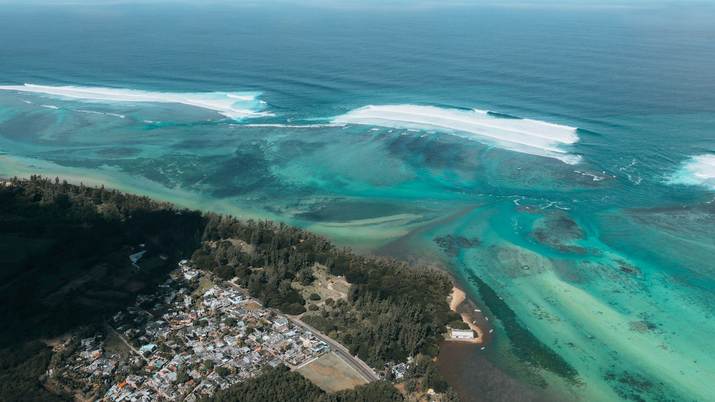 Waves breaking on the reef off the forested coast at Bel Ombre in the south of Mauritius, seen from the air.