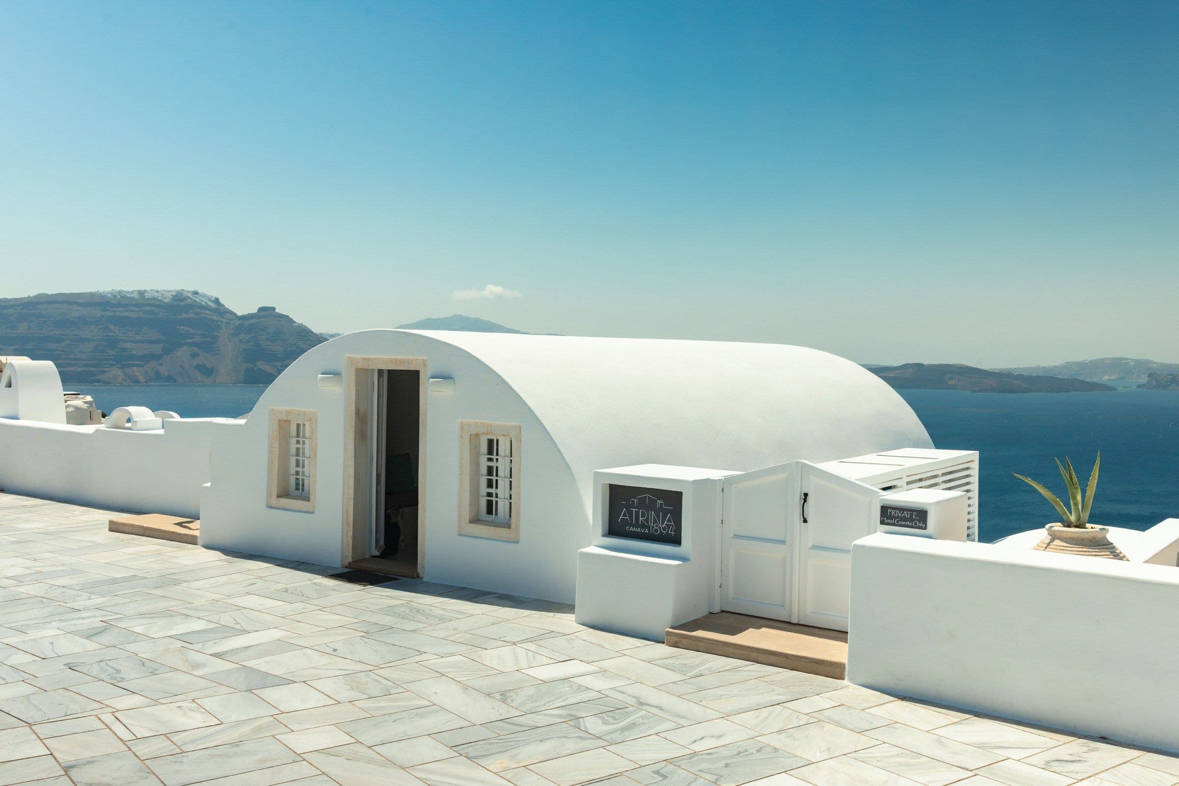 A whitewashed terrace and domed suite overlooking the caldera in Santorini, Greece.