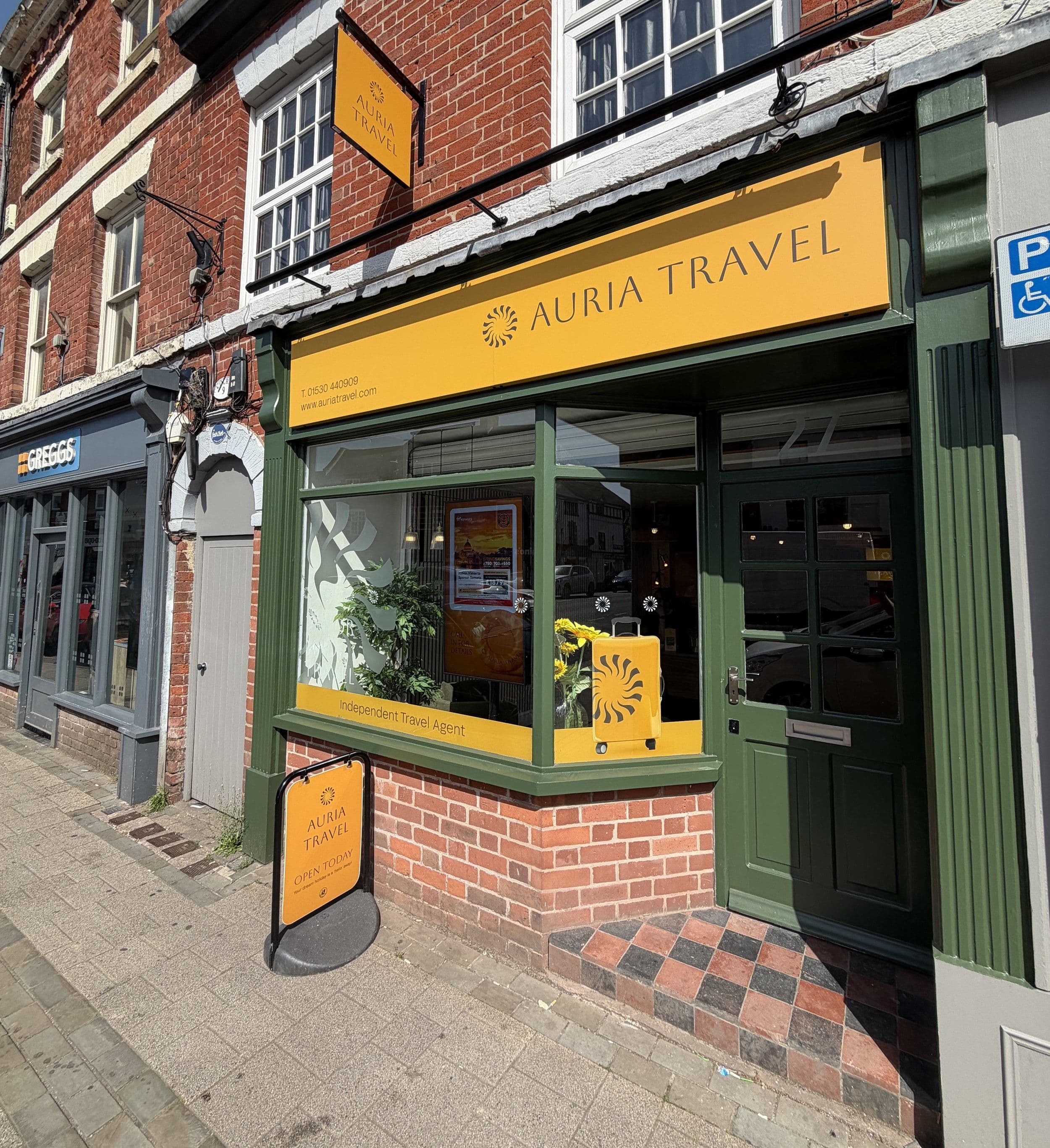 The Auria Travel store front on Market Street, Ashby de la Zouch: a yellow fascia with the Auria Travel name above a green-framed window and door.