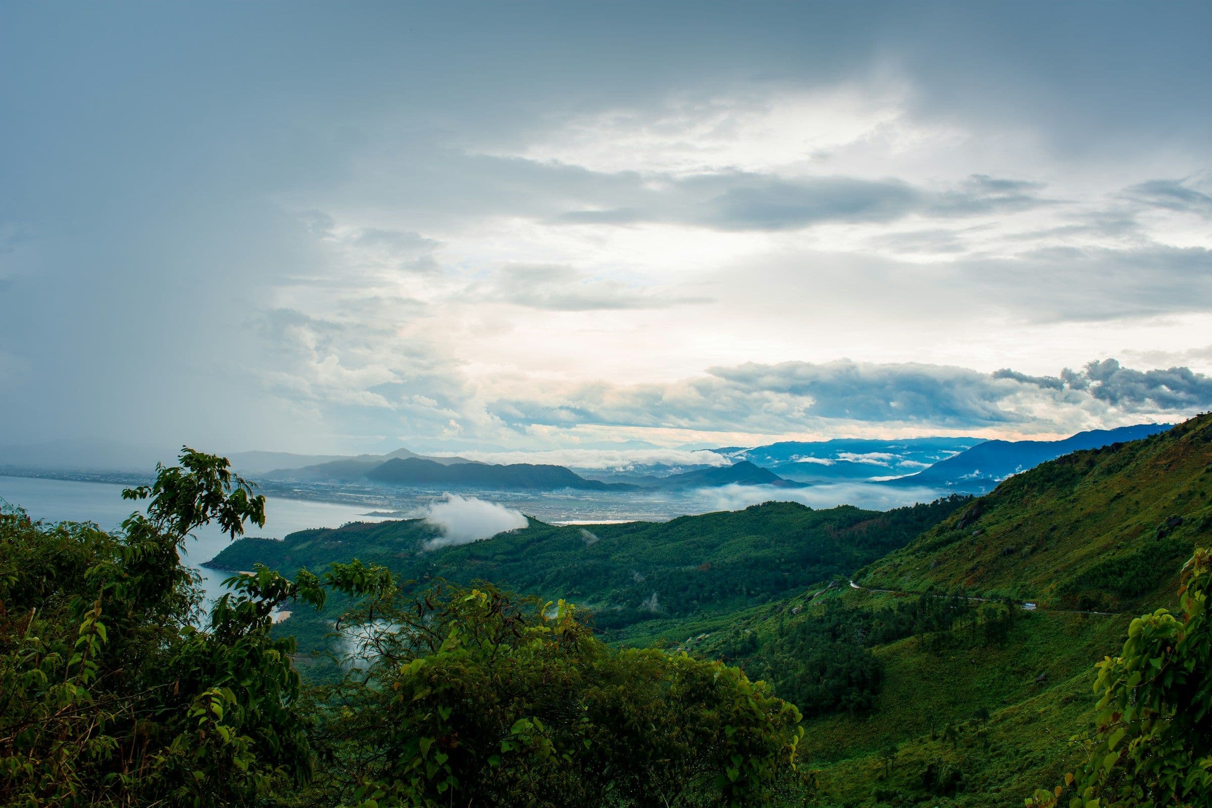 Forested hills falling to the sea under heavy cloud, seen from the Hai Van Pass in central Vietnam.