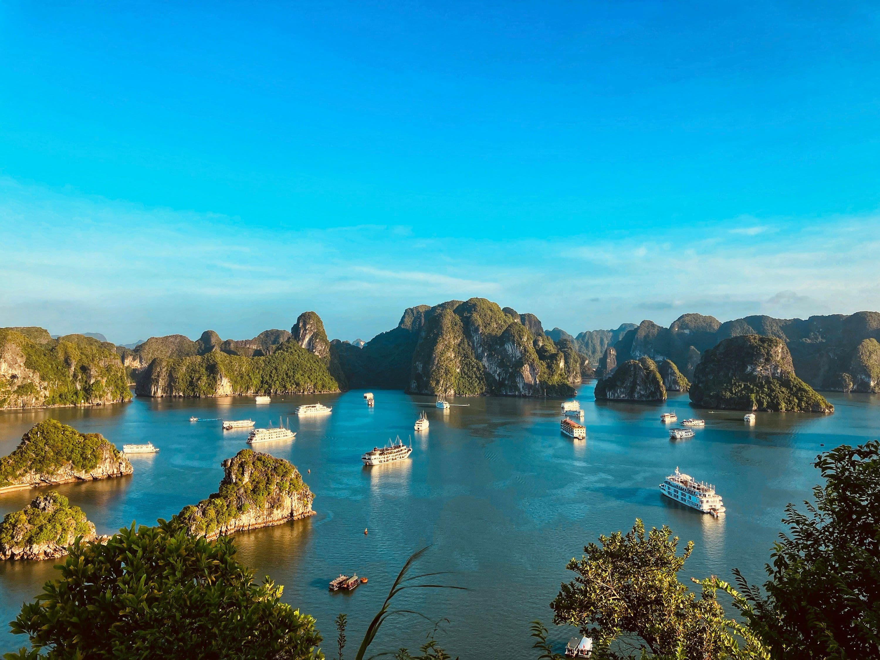 Boats at anchor among the limestone islands of Ha Long Bay, Vietnam, in warm evening light.