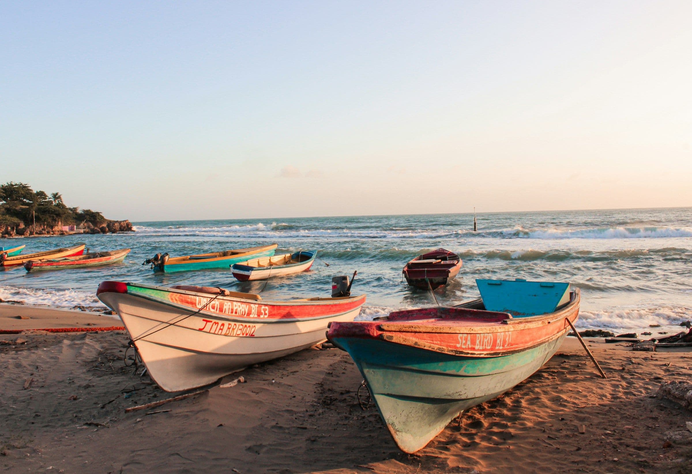 Painted wooden fishing boats drawn up on the sand at Treasure Beach, Jamaica.