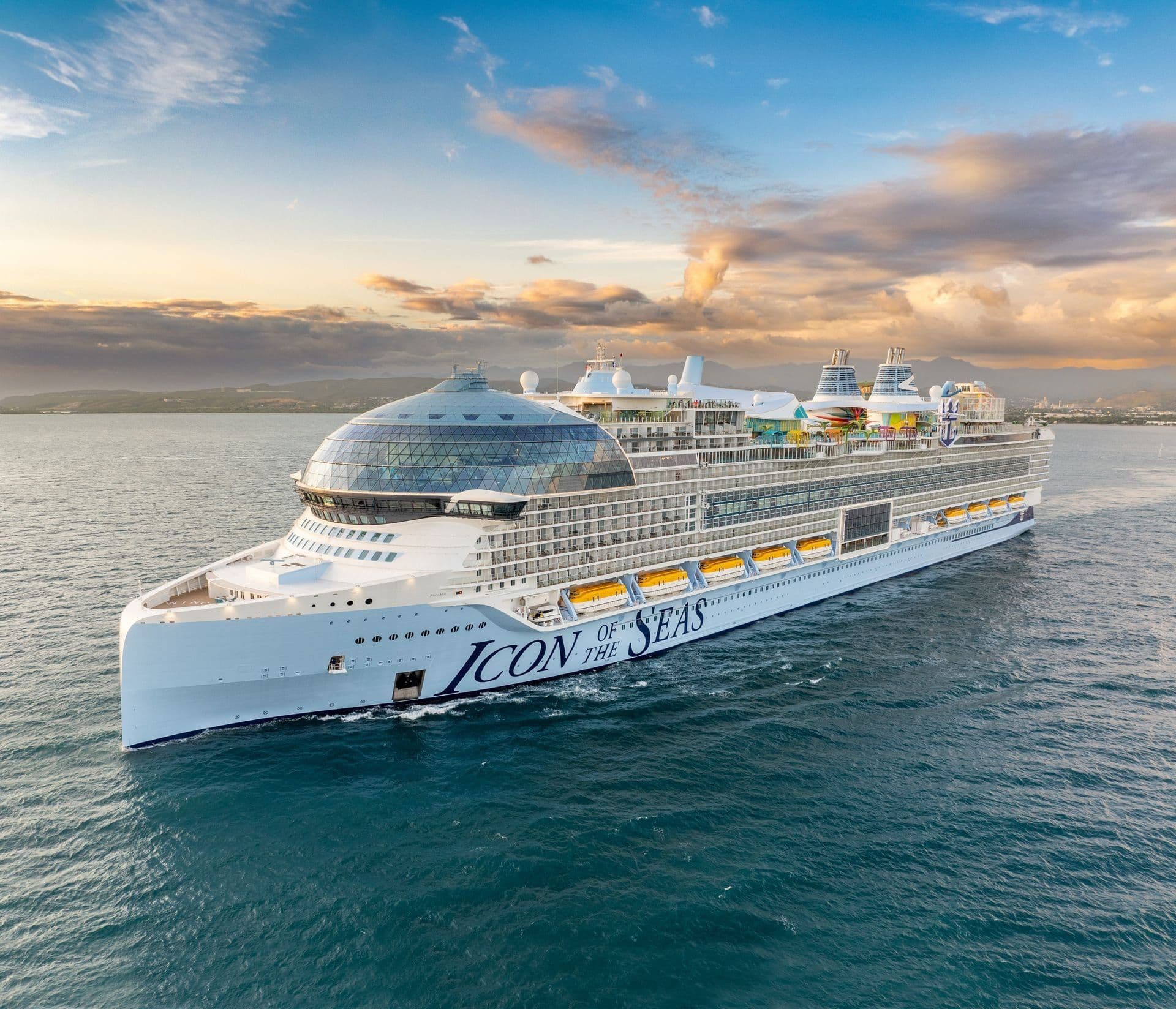 The cruise ship Icon of the Seas at sea under a colourful evening sky.