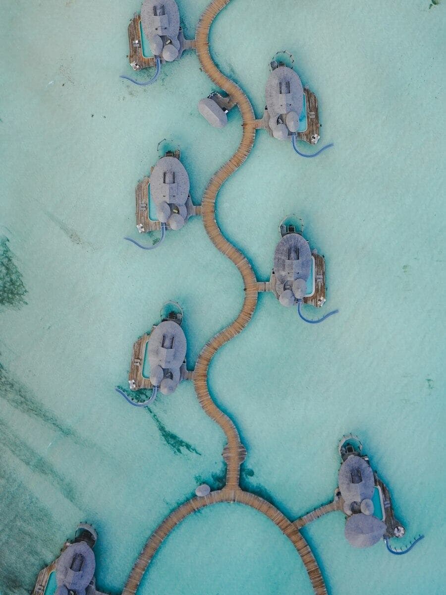 Overwater bungalows joined by curving wooden walkways.
