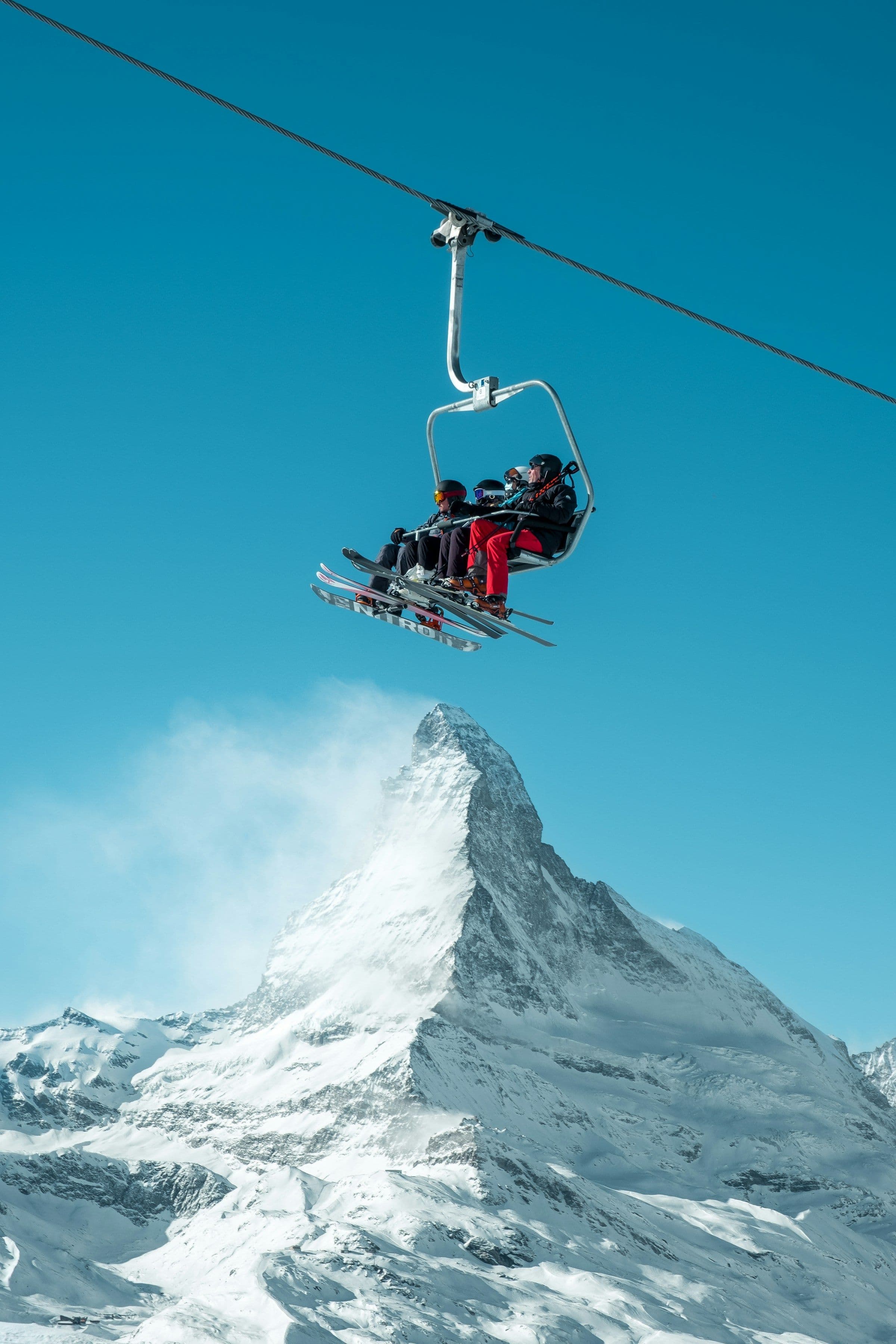 A chairlift carrying skiers high above the snow, with the Matterhorn behind.
