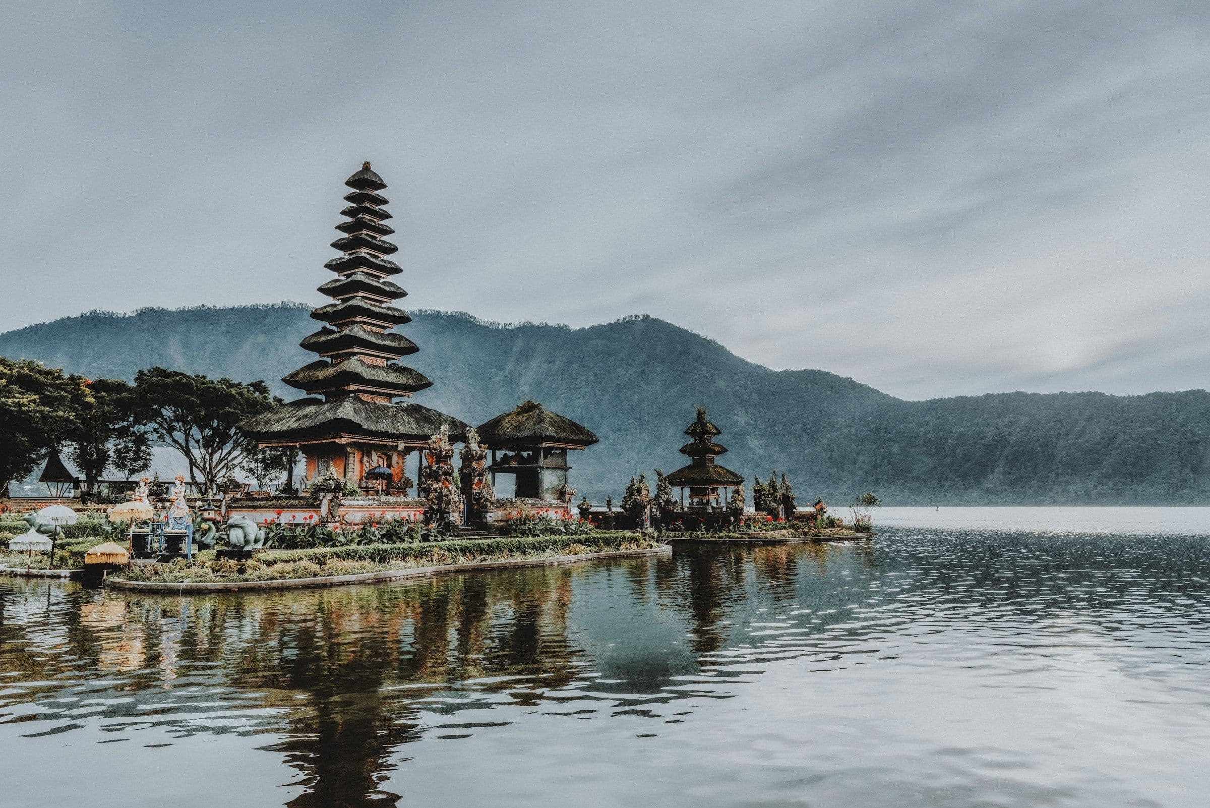 The tiered shrines of the Ulun Danu Beratan temple at the edge of a lake in the mountains of Bali, under cloud.
