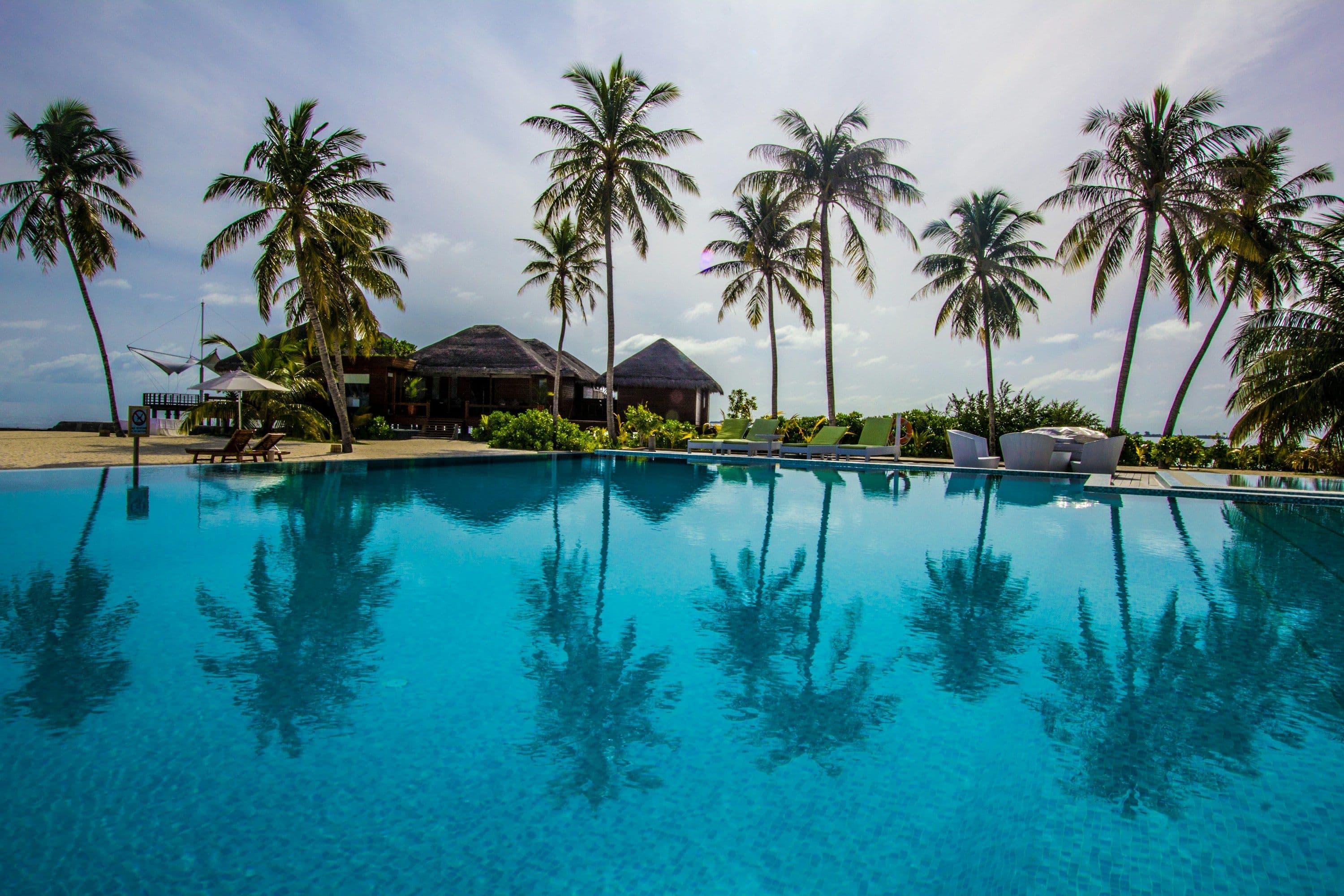Palm trees reflected in a calm resort swimming pool in the Maldives.