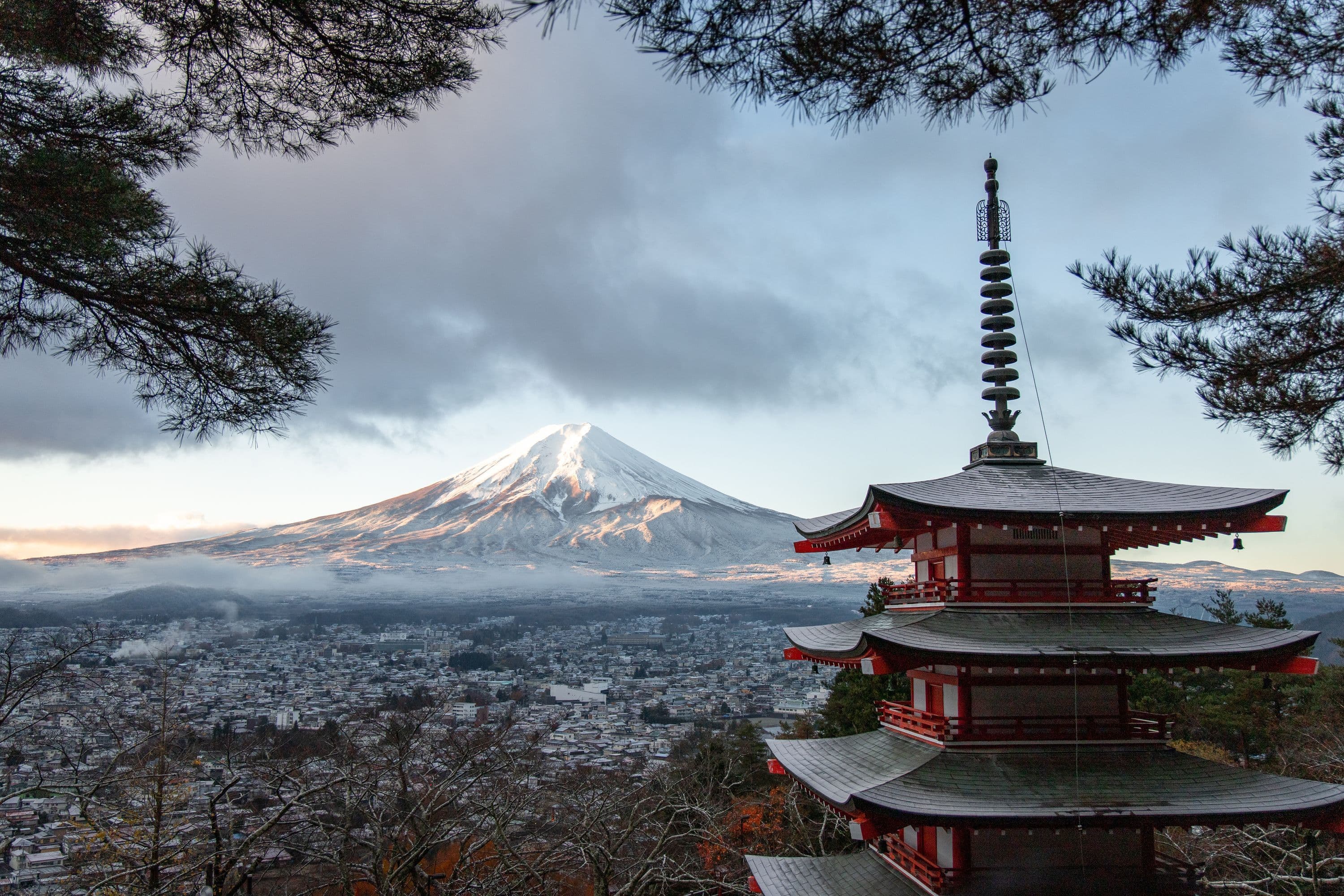The red Chureito Pagoda overlooking a town and snow-capped Mount Fuji in Japan.