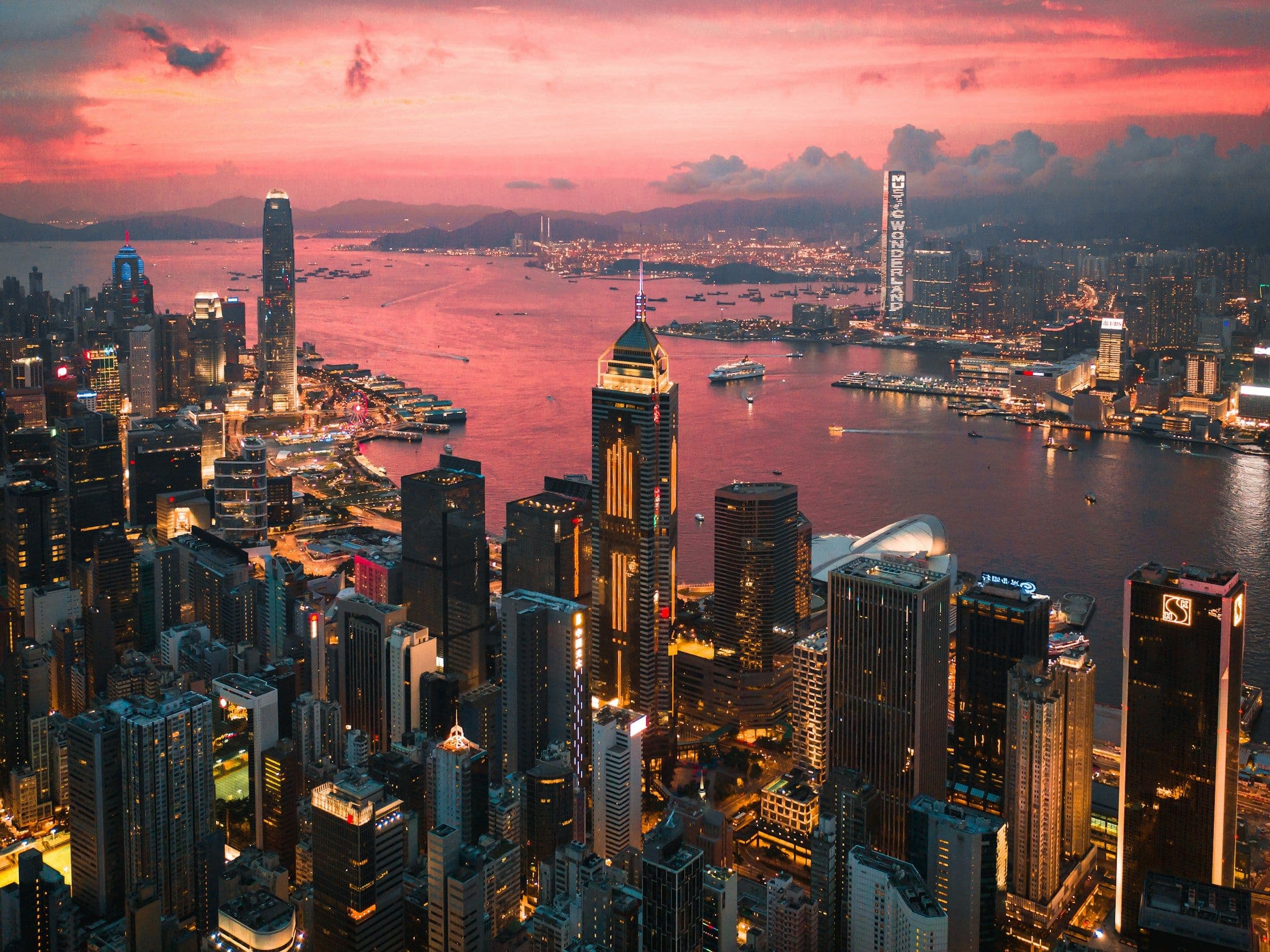 The skyscrapers of Hong Kong around Victoria Harbour at sunset.